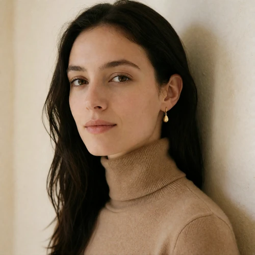 Portrait of a woman in a camel roll-neck against a warm alabaster wall