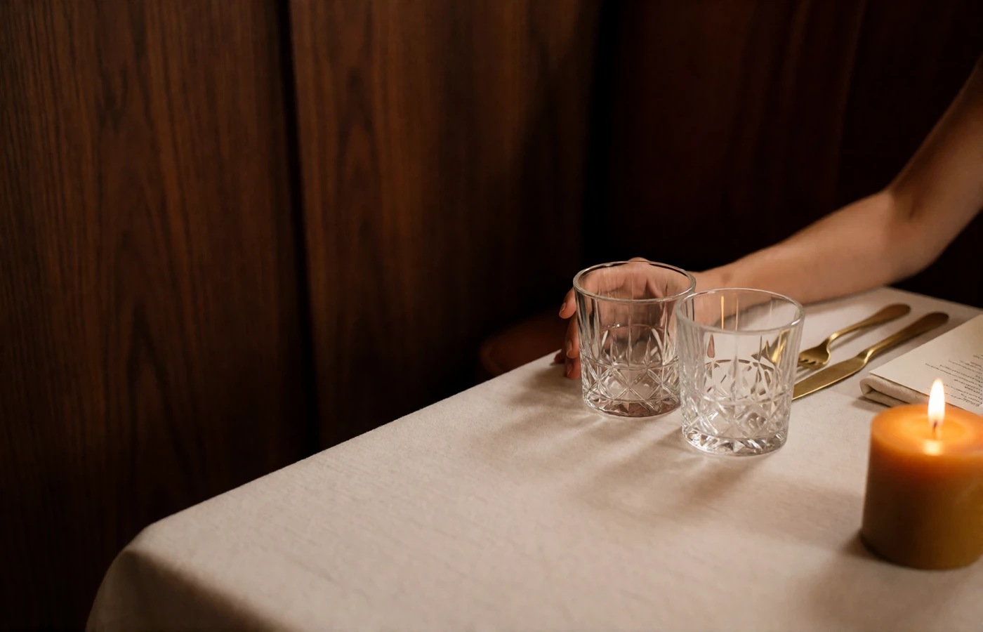 Quiet corner table set for dinner at an upscale Houston steakhouse with linen, crystal glassware and low candlelight